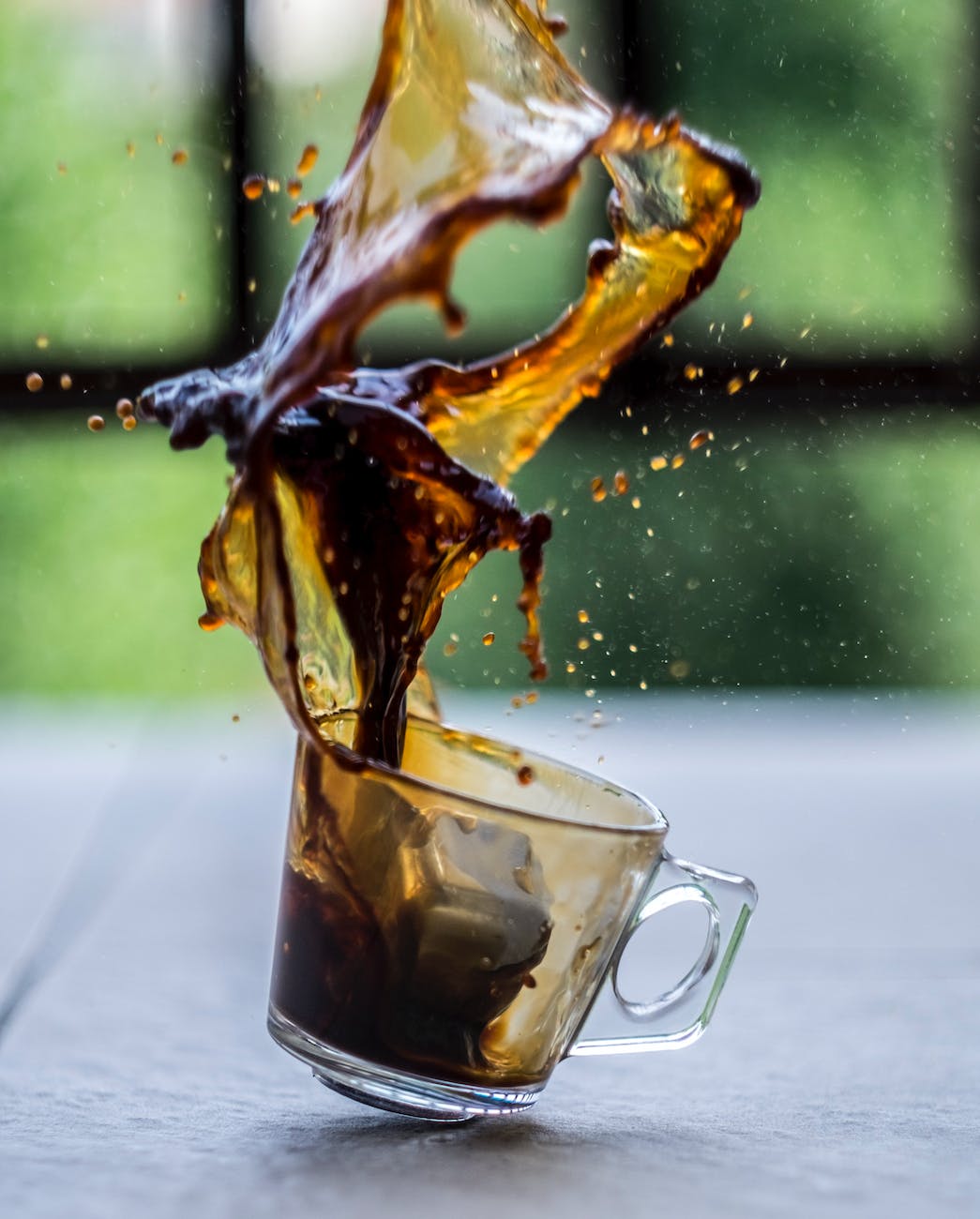 transparent cup with coffee splattered in air
