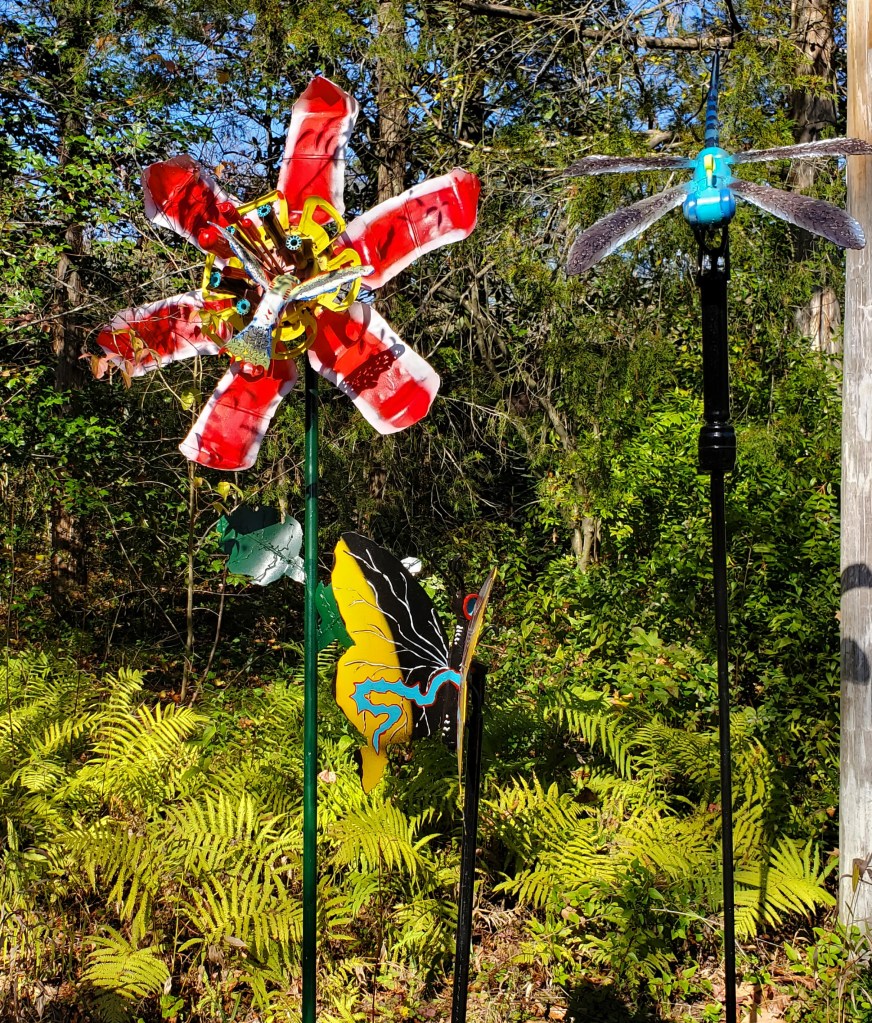 red metal flower with humming bird, butterfly and dragonfly art each on a separate pole.
